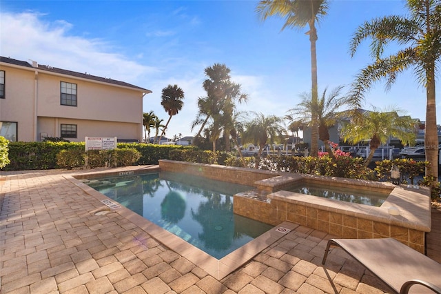 view of pool with a hot tub and a patio