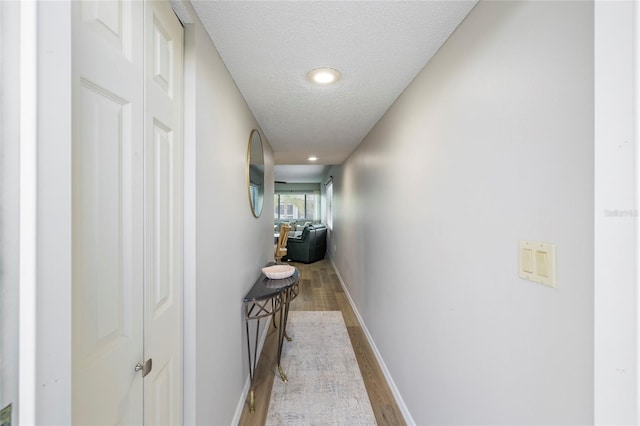 corridor featuring light hardwood / wood-style flooring and a textured ceiling