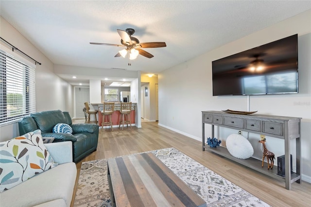 living room with ceiling fan, a healthy amount of sunlight, and light wood-type flooring