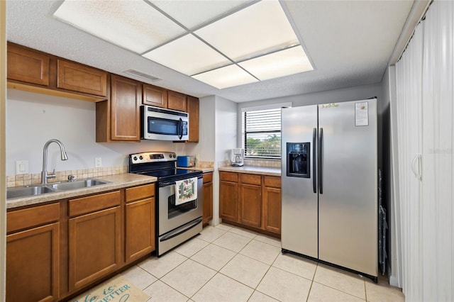 kitchen with sink, light tile patterned floors, and appliances with stainless steel finishes