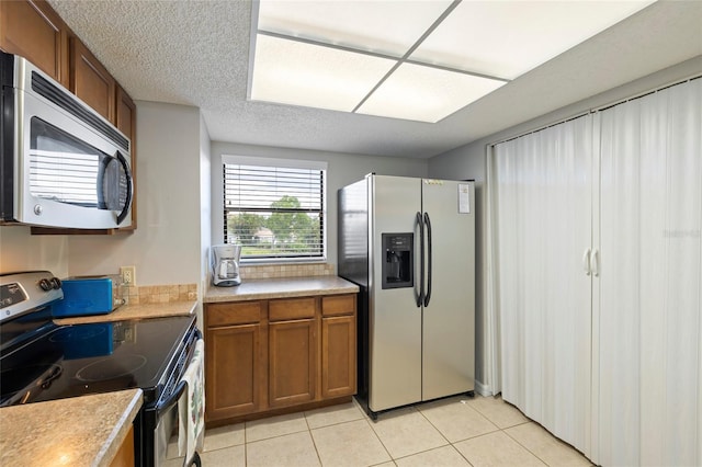 kitchen with appliances with stainless steel finishes, a textured ceiling, and light tile patterned floors