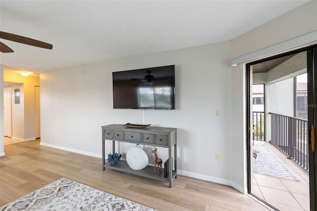 living room featuring a textured ceiling, light hardwood / wood-style flooring, and ceiling fan