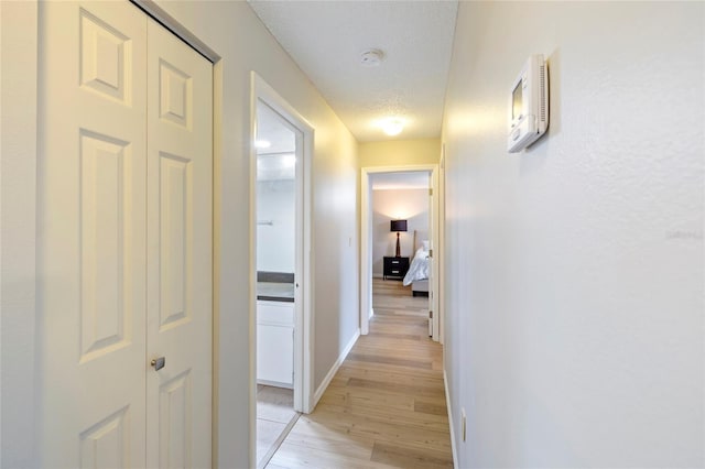 hallway with a textured ceiling and light wood-type flooring