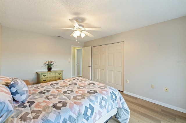 bedroom with a textured ceiling, a closet, ceiling fan, and light wood-type flooring