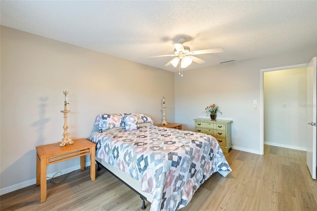 bedroom with a textured ceiling, light hardwood / wood-style floors, and ceiling fan