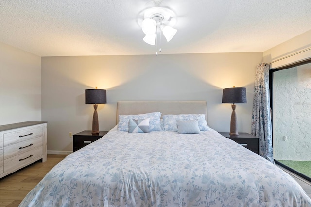 bedroom featuring a textured ceiling, ceiling fan, and light wood-type flooring