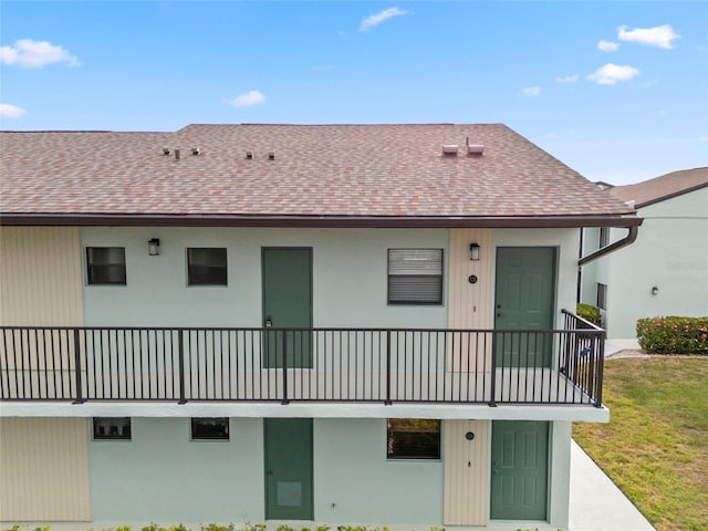 back of property featuring a balcony and a lawn