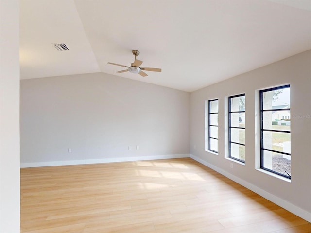 empty room with lofted ceiling, plenty of natural light, light wood-type flooring, and ceiling fan