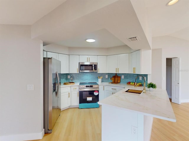 kitchen with sink, white cabinets, kitchen peninsula, and appliances with stainless steel finishes