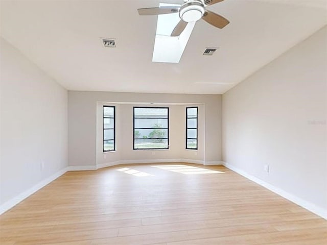 unfurnished room featuring ceiling fan, a skylight, and light hardwood / wood-style floors