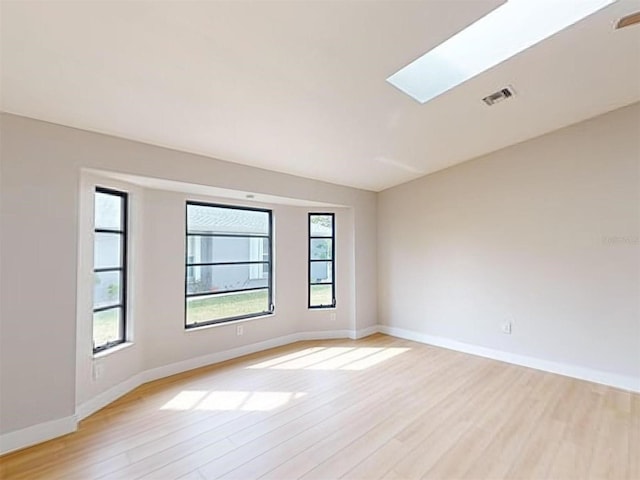 spare room featuring light hardwood / wood-style flooring and a skylight