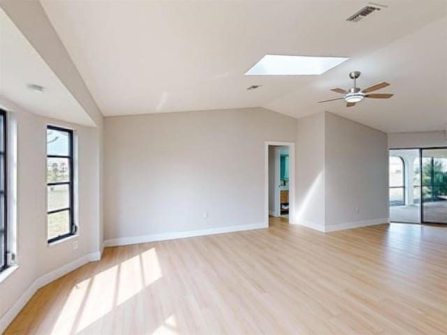 spare room featuring light wood-type flooring, lofted ceiling with skylight, and a healthy amount of sunlight