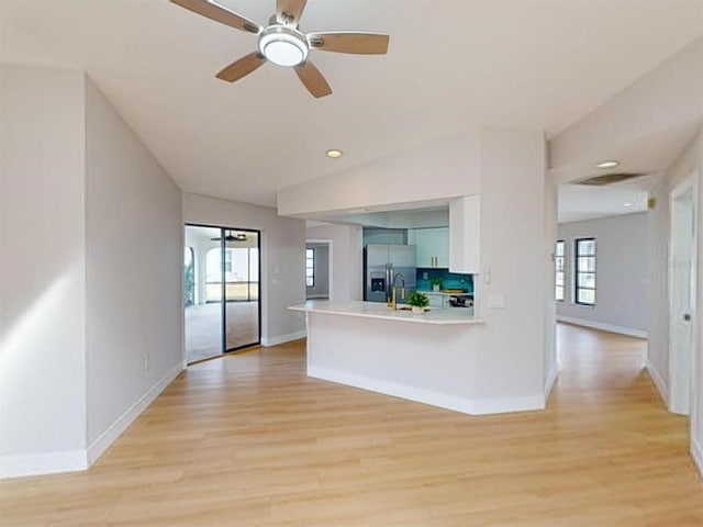 kitchen featuring stainless steel refrigerator with ice dispenser, white cabinetry, tasteful backsplash, kitchen peninsula, and light wood-type flooring