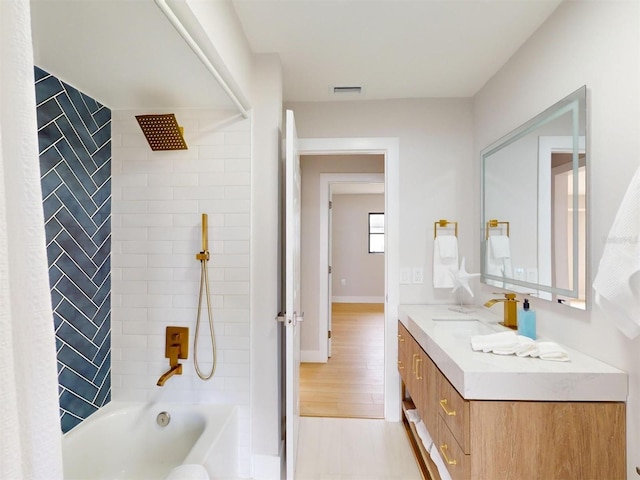 bathroom featuring tiled shower / bath combo and vanity