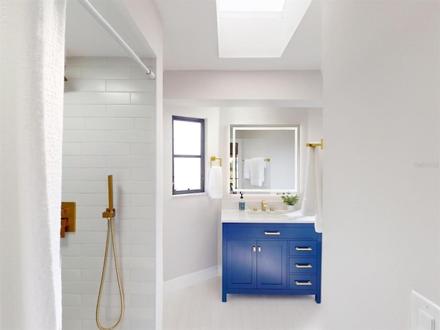 bathroom featuring vanity, a skylight, and a shower