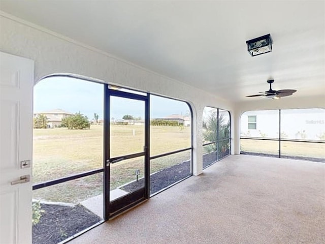 unfurnished sunroom featuring ceiling fan