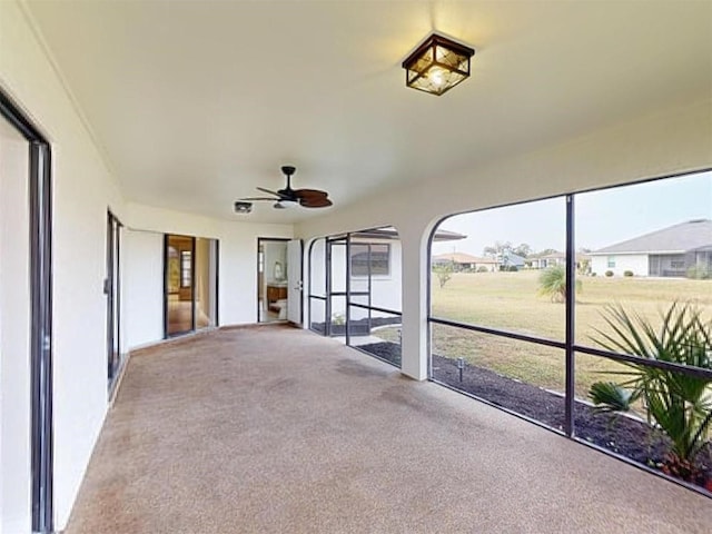 unfurnished sunroom featuring ceiling fan and a healthy amount of sunlight