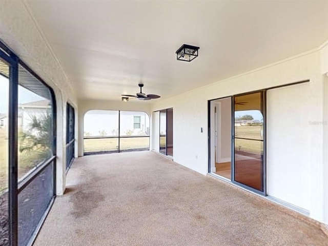 unfurnished sunroom featuring ceiling fan and a wealth of natural light