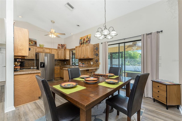 dining room featuring vaulted ceiling, ceiling fan with notable chandelier, and light hardwood / wood-style flooring