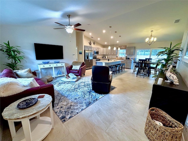 living room with lofted ceiling, sink, and ceiling fan with notable chandelier