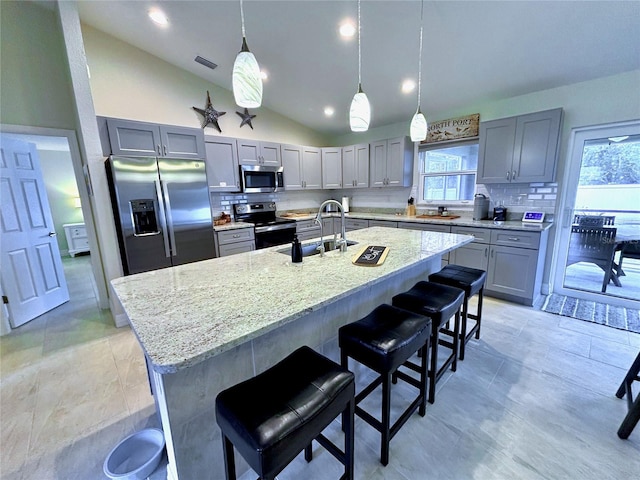 kitchen featuring appliances with stainless steel finishes, sink, a center island with sink, and lofted ceiling