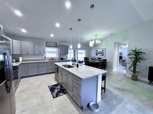 kitchen with lofted ceiling, sink, a kitchen island with sink, gray cabinetry, and decorative light fixtures