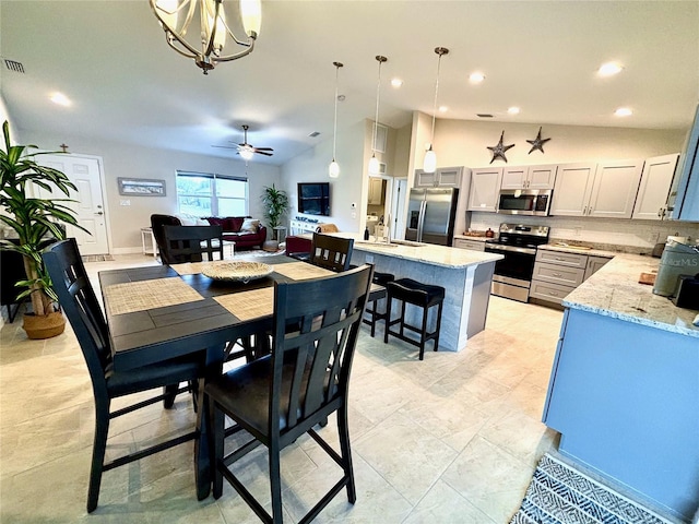 dining space featuring lofted ceiling, sink, and ceiling fan with notable chandelier