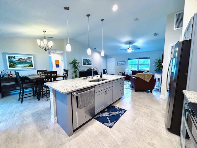 kitchen with lofted ceiling, sink, decorative light fixtures, stainless steel appliances, and light stone countertops