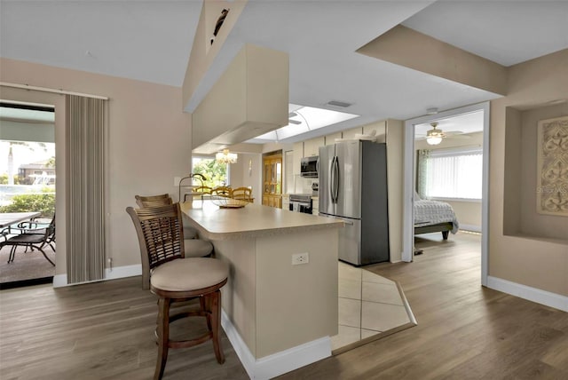 kitchen with stainless steel appliances, light hardwood / wood-style flooring, kitchen peninsula, and a breakfast bar area