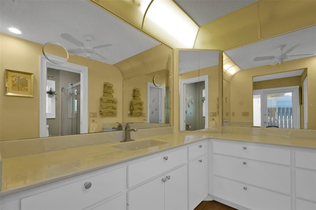 bathroom featuring a shower with shower door, ceiling fan, and vanity