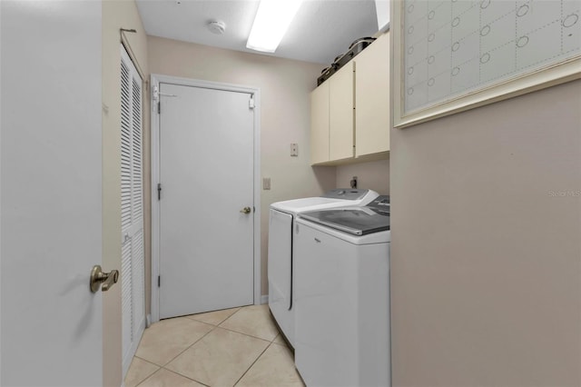 laundry room with cabinets, light tile patterned floors, and washing machine and clothes dryer