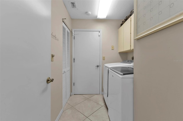 washroom featuring independent washer and dryer, cabinets, and light tile patterned flooring