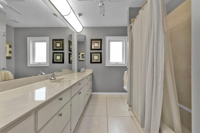 bathroom with vanity, ceiling fan, a healthy amount of sunlight, and tile patterned flooring