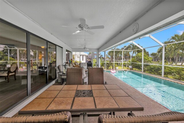 view of swimming pool with glass enclosure, a patio, and ceiling fan