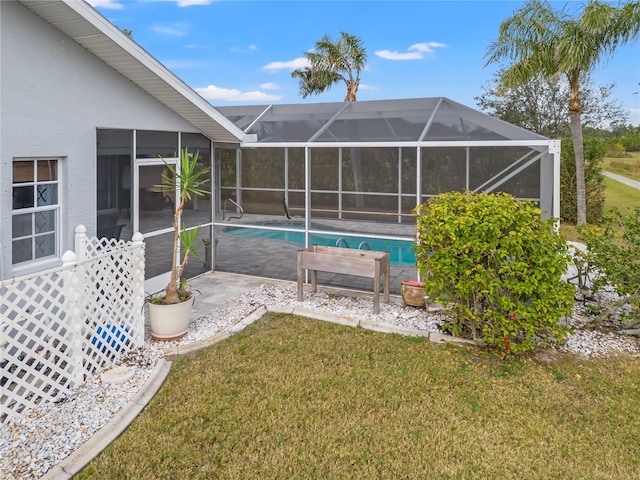 view of pool with glass enclosure, a yard, and a patio