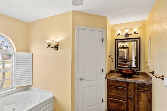 bathroom with a textured ceiling, vanity, and a bath