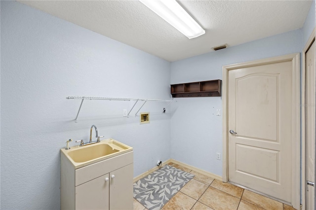 laundry room with a textured ceiling, washer hookup, light tile patterned floors, sink, and cabinets