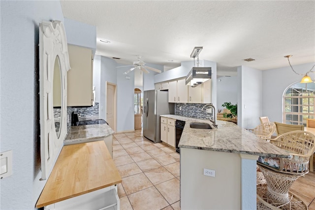 kitchen with stainless steel refrigerator with ice dispenser, decorative backsplash, sink, kitchen peninsula, and light stone counters