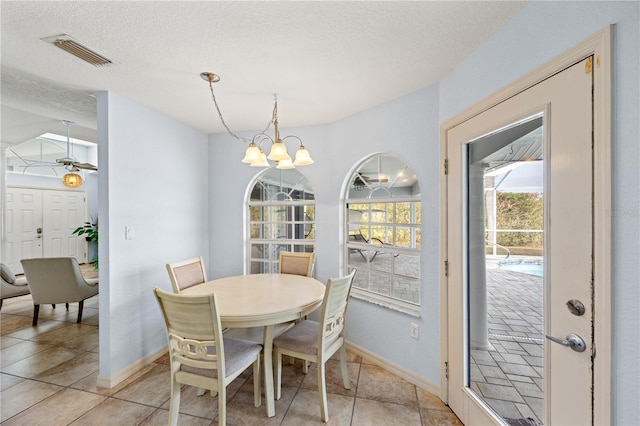 dining room featuring light tile patterned flooring, a textured ceiling, and an inviting chandelier