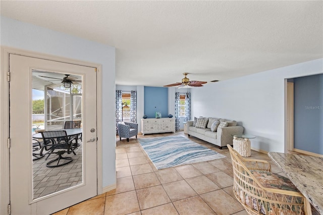 living room with a textured ceiling, light tile patterned floors, and ceiling fan