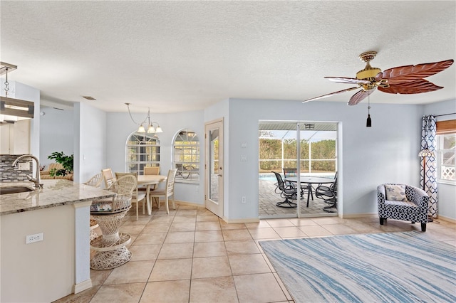 interior space featuring sink, ceiling fan with notable chandelier, and a textured ceiling