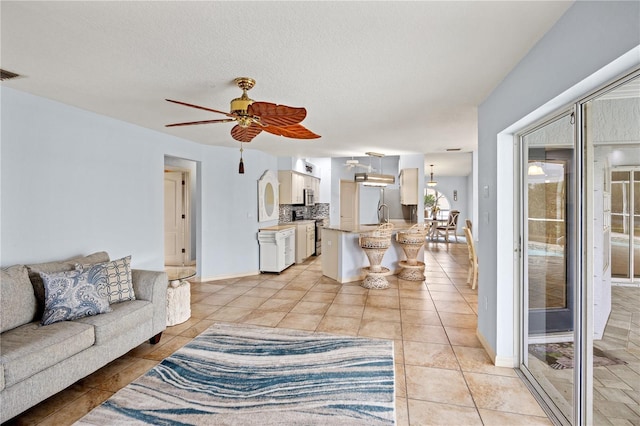 tiled living room featuring ceiling fan and a textured ceiling