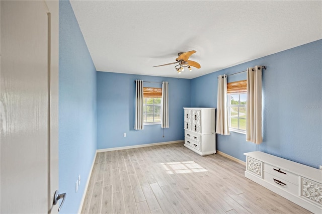 unfurnished bedroom featuring ceiling fan, light hardwood / wood-style flooring, a textured ceiling, and multiple windows