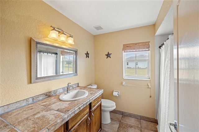 bathroom featuring vanity, toilet, a wealth of natural light, and tile patterned floors