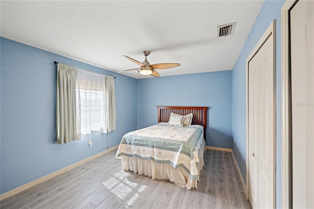 bedroom featuring wood-type flooring, a textured ceiling, a closet, and ceiling fan