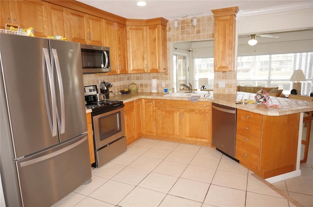 kitchen with sink, kitchen peninsula, appliances with stainless steel finishes, and decorative backsplash