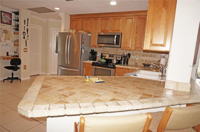 kitchen featuring sink, kitchen peninsula, backsplash, stainless steel appliances, and tile countertops