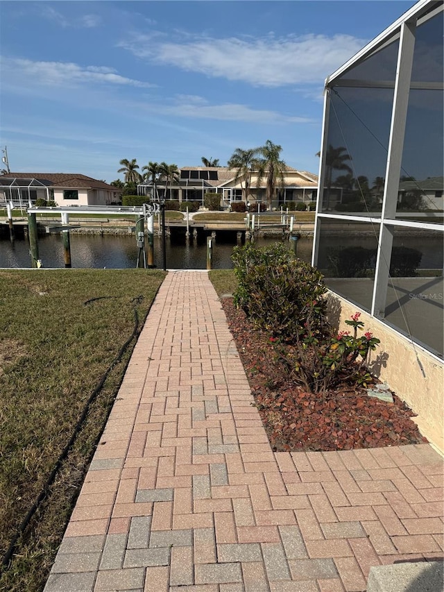 view of dock featuring a lawn, a lanai, and a water view