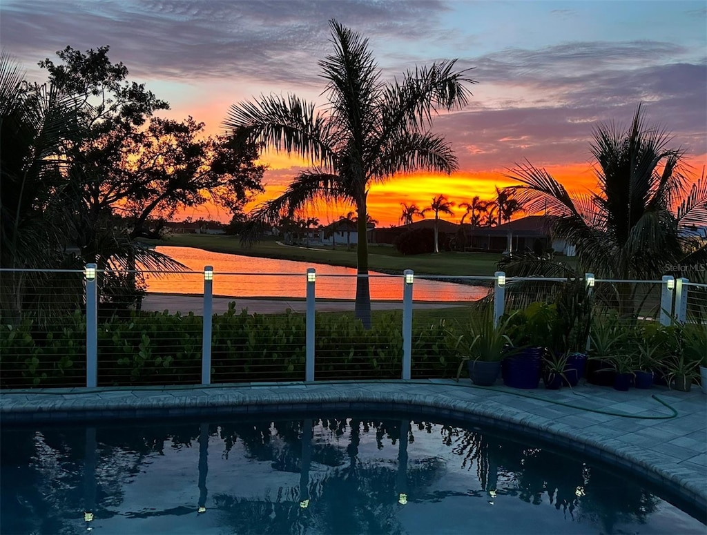 pool at dusk featuring a water view