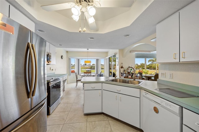 kitchen with sink, stainless steel appliances, a raised ceiling, white cabinets, and kitchen peninsula